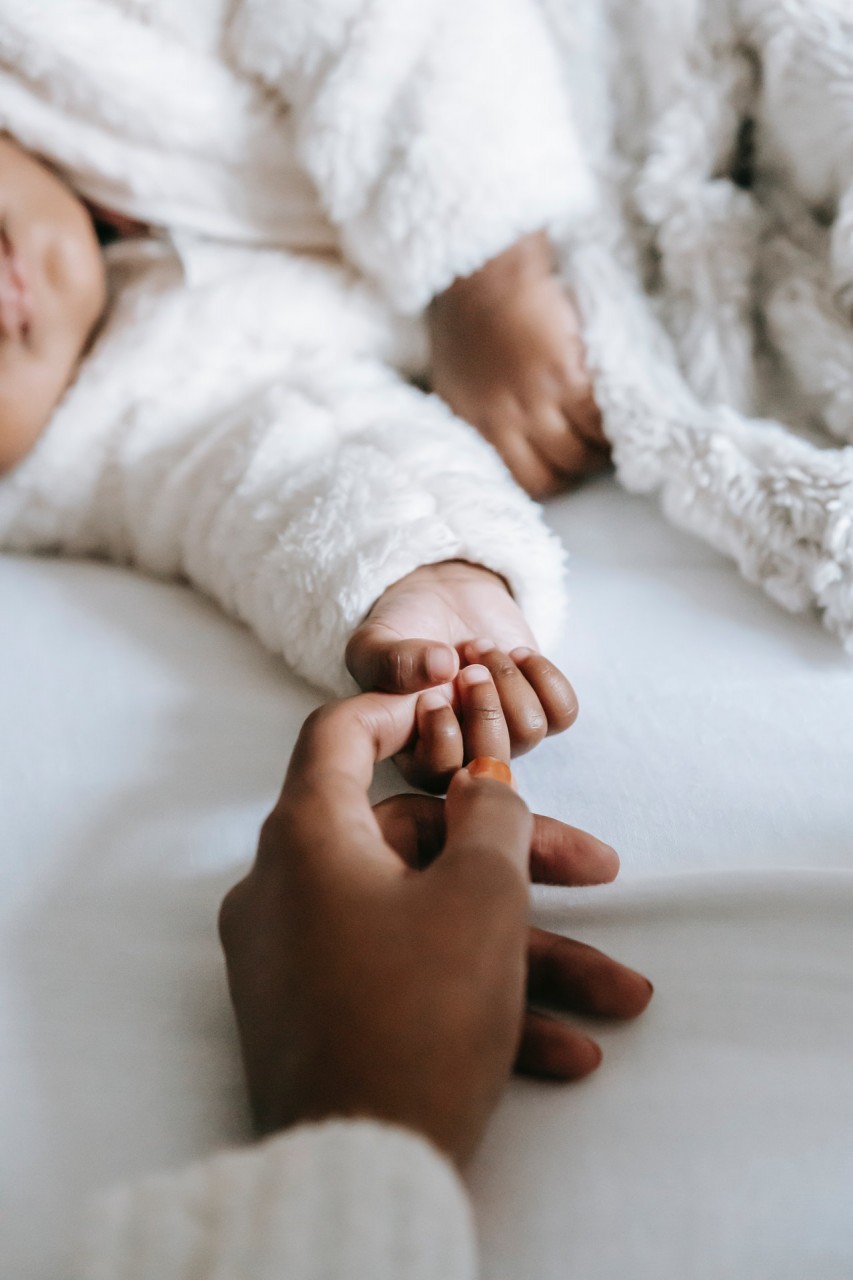 Mother suffering from Postpartum depression holding her baby's finger