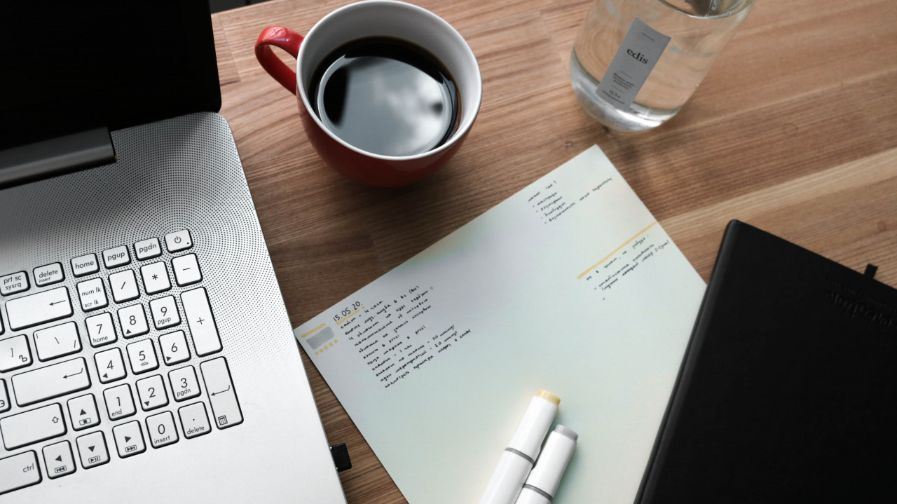 A jotter with notes and a laptop.