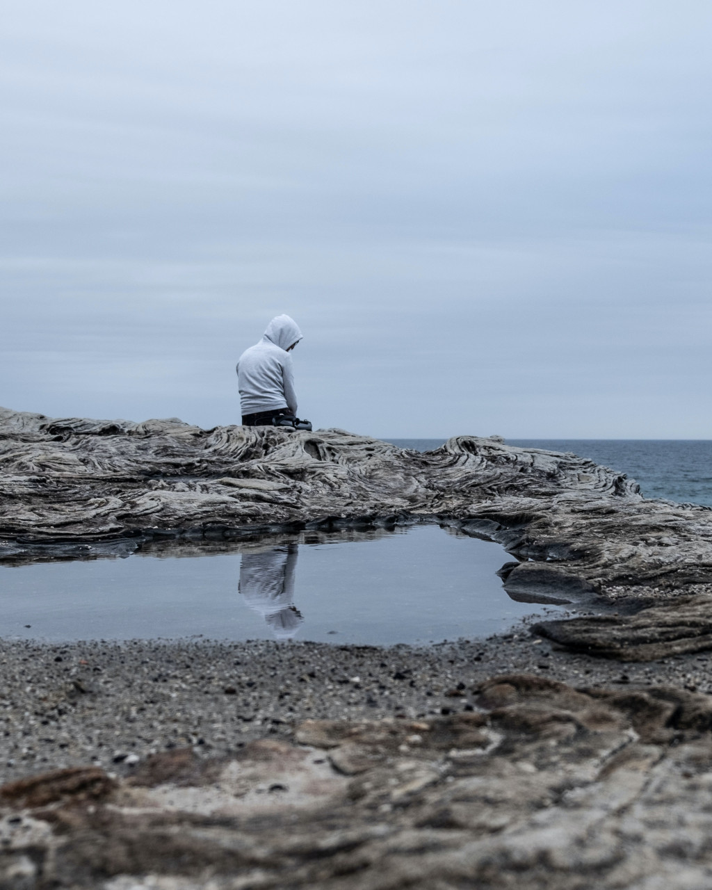 A man sitting beside a pool of water.