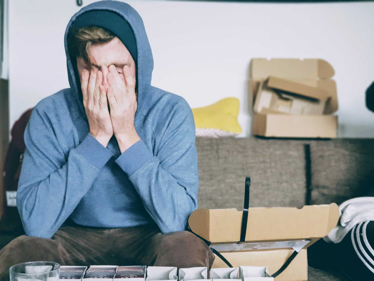 a man wearing a hoodie with his face in his palms