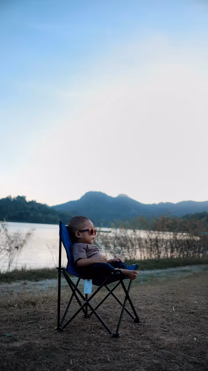 A boy lounging on a chair outdoors.