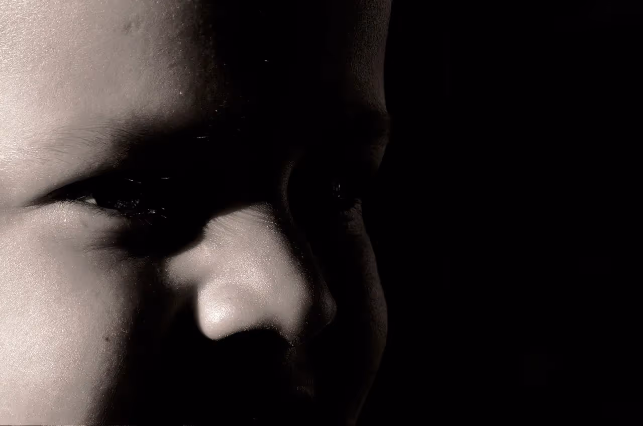 A face in the dark with a shadow cast over it.