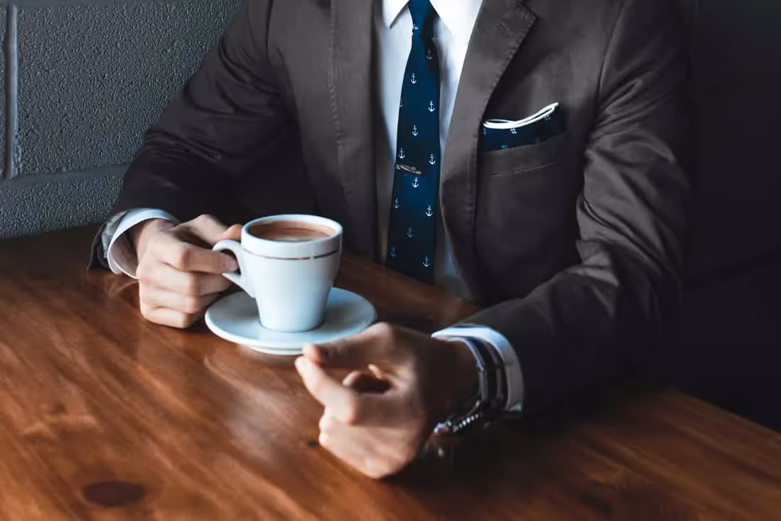 a man in a power suit drinking coffee