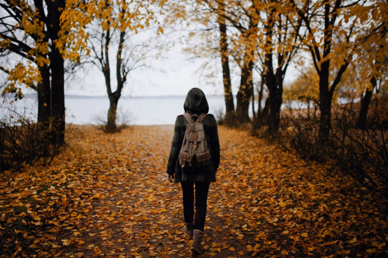 Woman walking on a path with fall leaves.