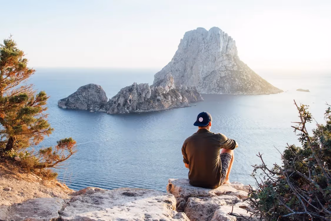 Man sitting on rocks looking at the ocean