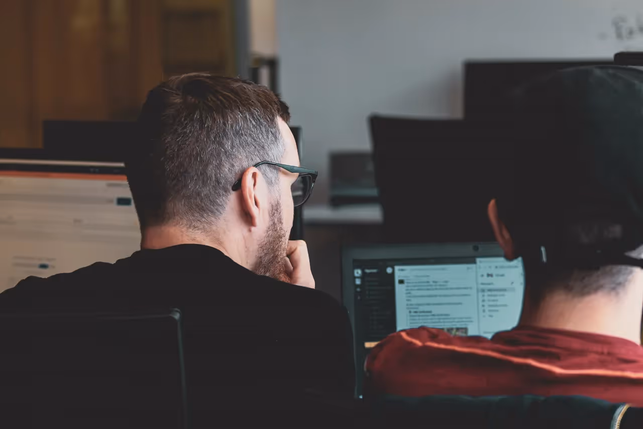 Two men sitting in front of a computer