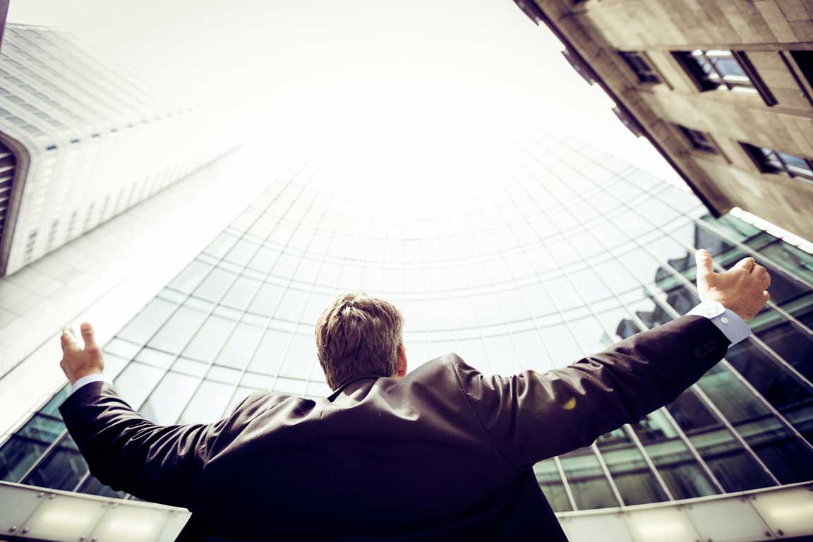 a person looking up triumphantly at an office building