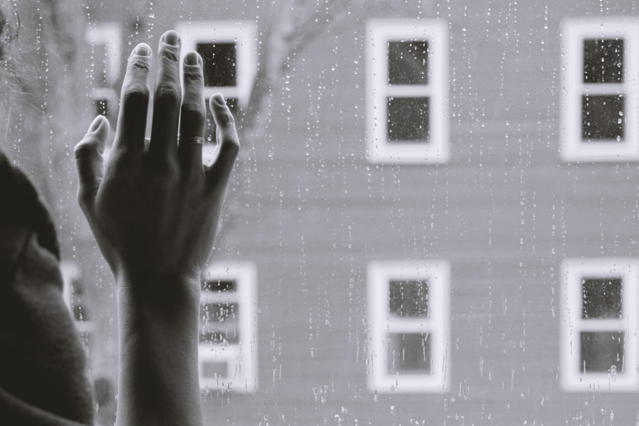 Person with their right hand on a window.