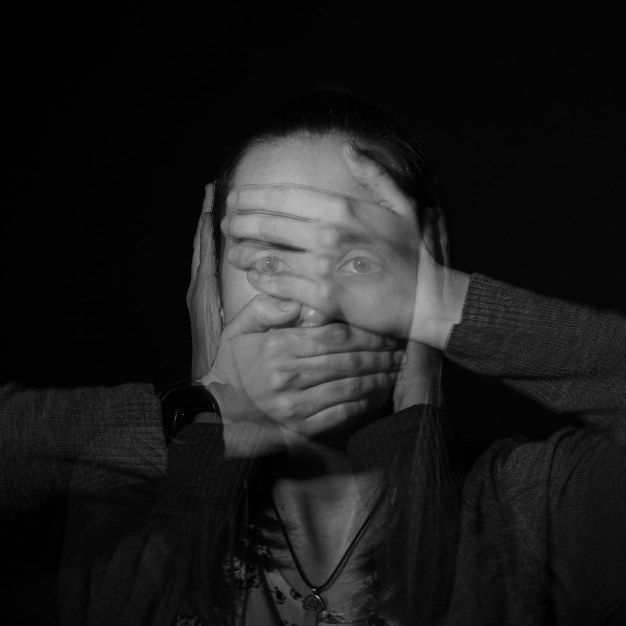 Hands over a person's eyes, mouth, and ears