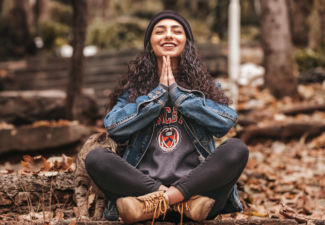 Woman sitting down outside on fall leaves Meditating.