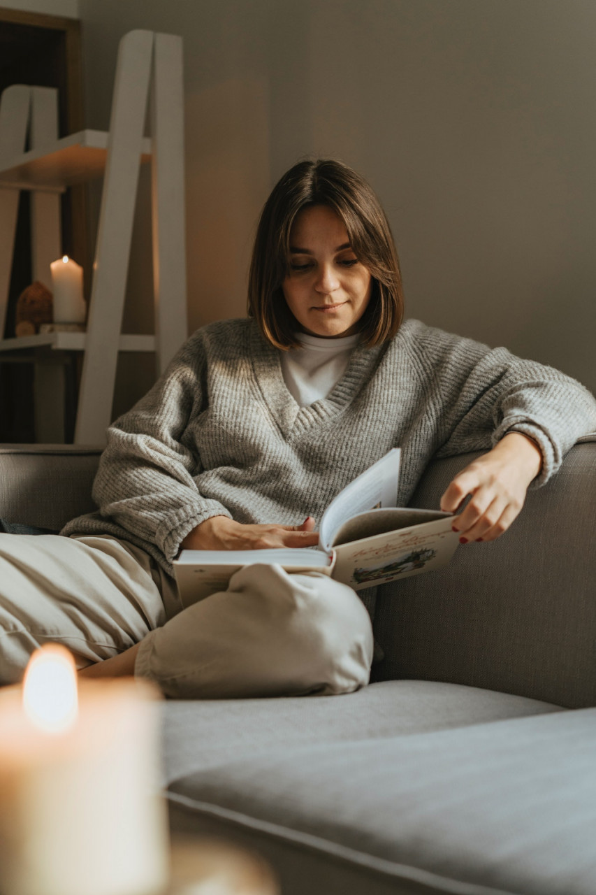 Woman sitting on a couch reading a book