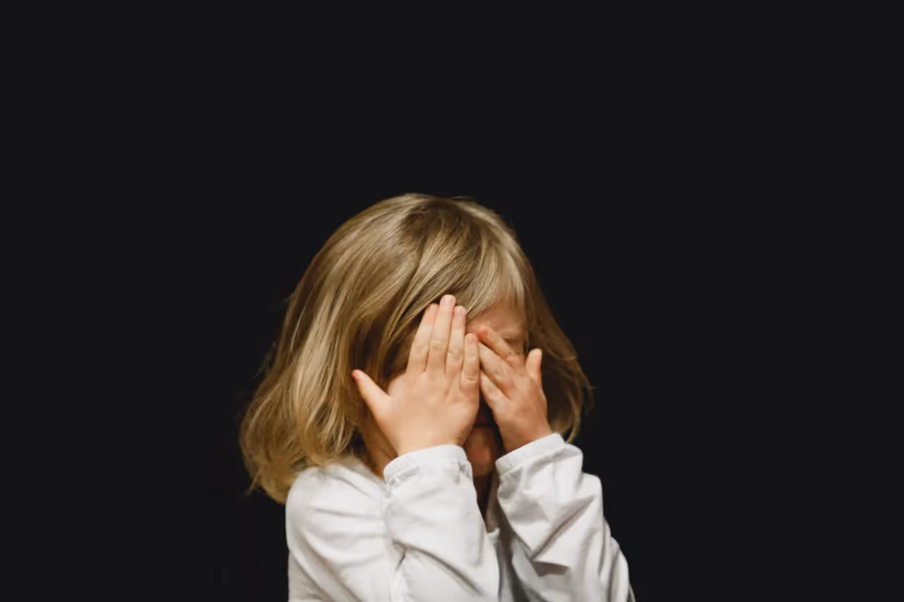 A child covering their eyes with their hands