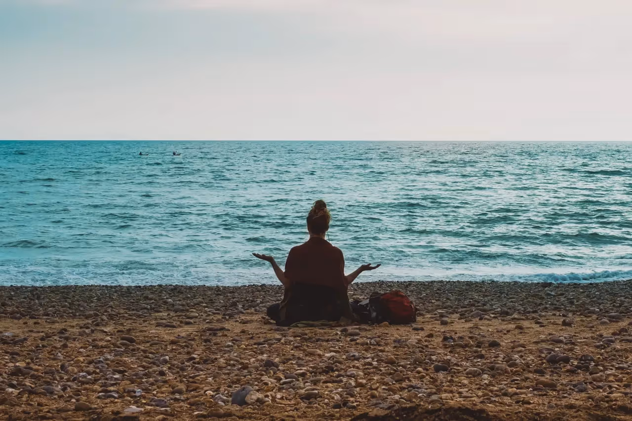 a woman sitting oceanside meditating