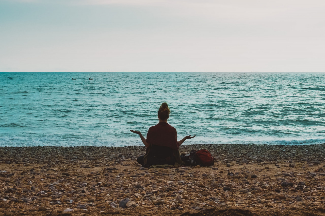 a woman sitting oceanside meditating
