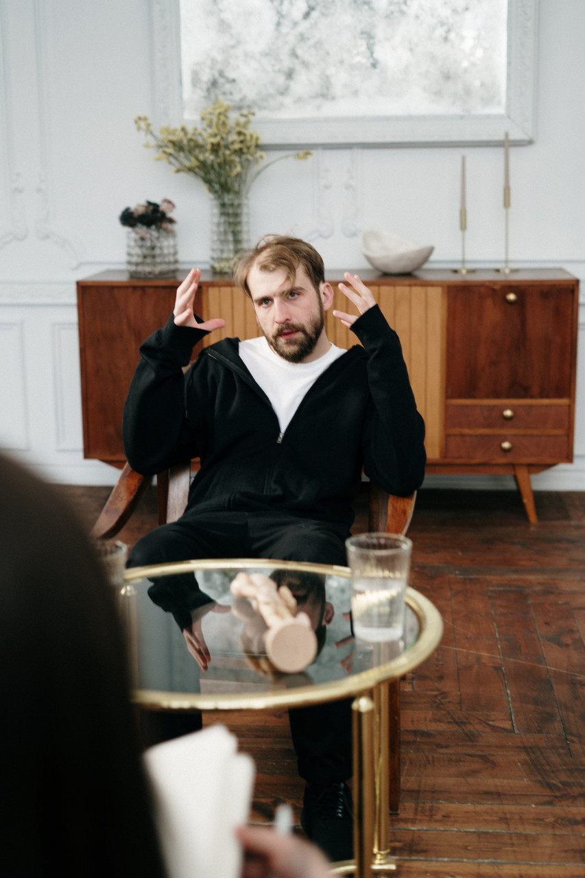 man in a black jacket sitting in a wooden chair