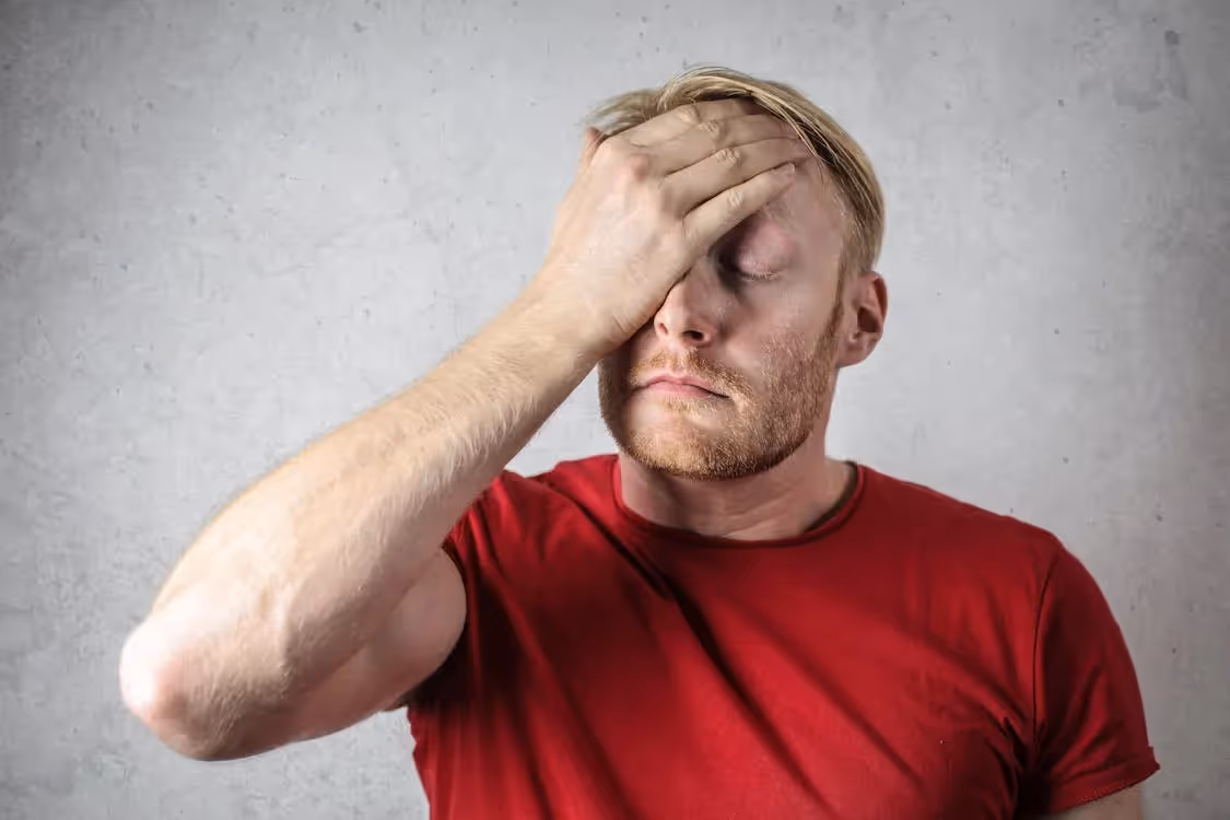 Man in red t-shirt holding his head
