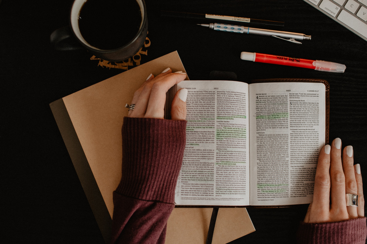 Woman sitting at desk reading a Bible