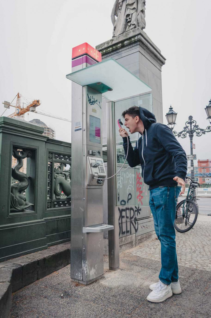 a teenager yelling into a payphone