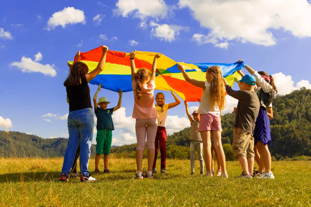 a group of children playing with a large parachute outside