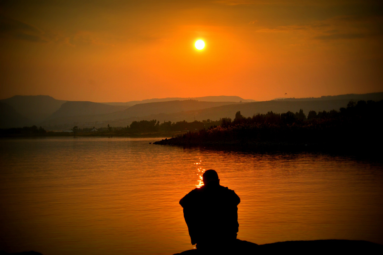 A person crying by a lake.