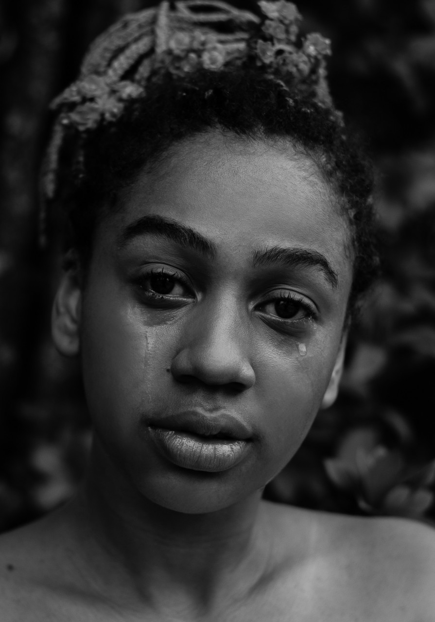 A lady crying while staring at the camera.