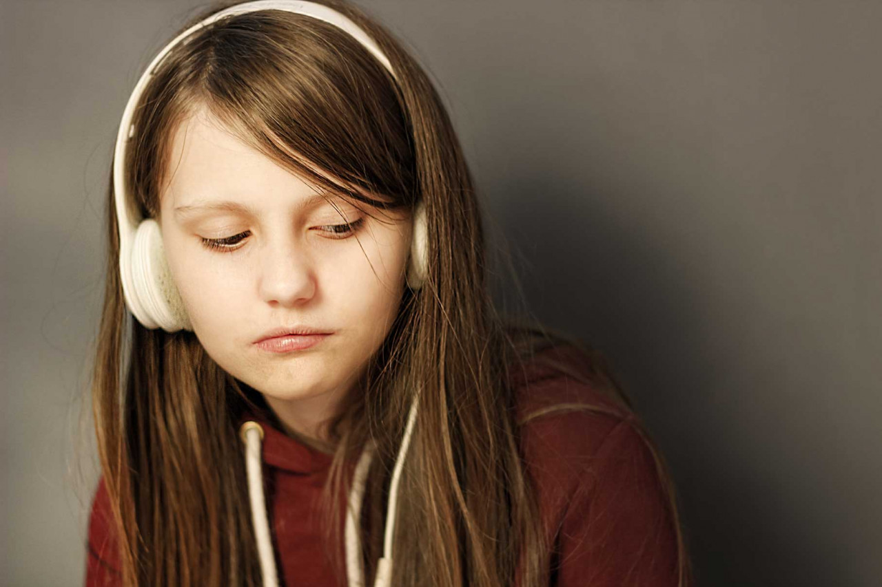a young teenager wearing headphones and looking down
