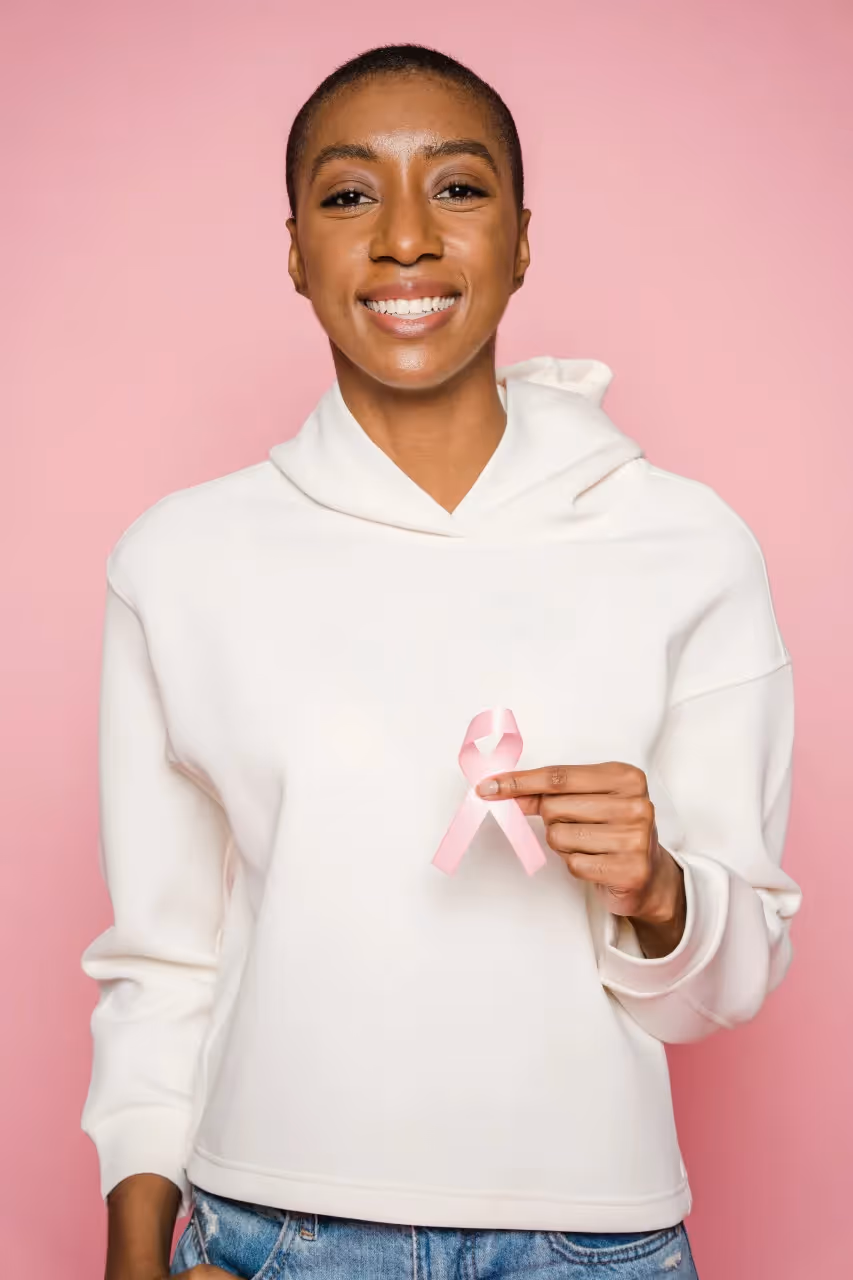 A lady holding the ribbon symbol of cancer.