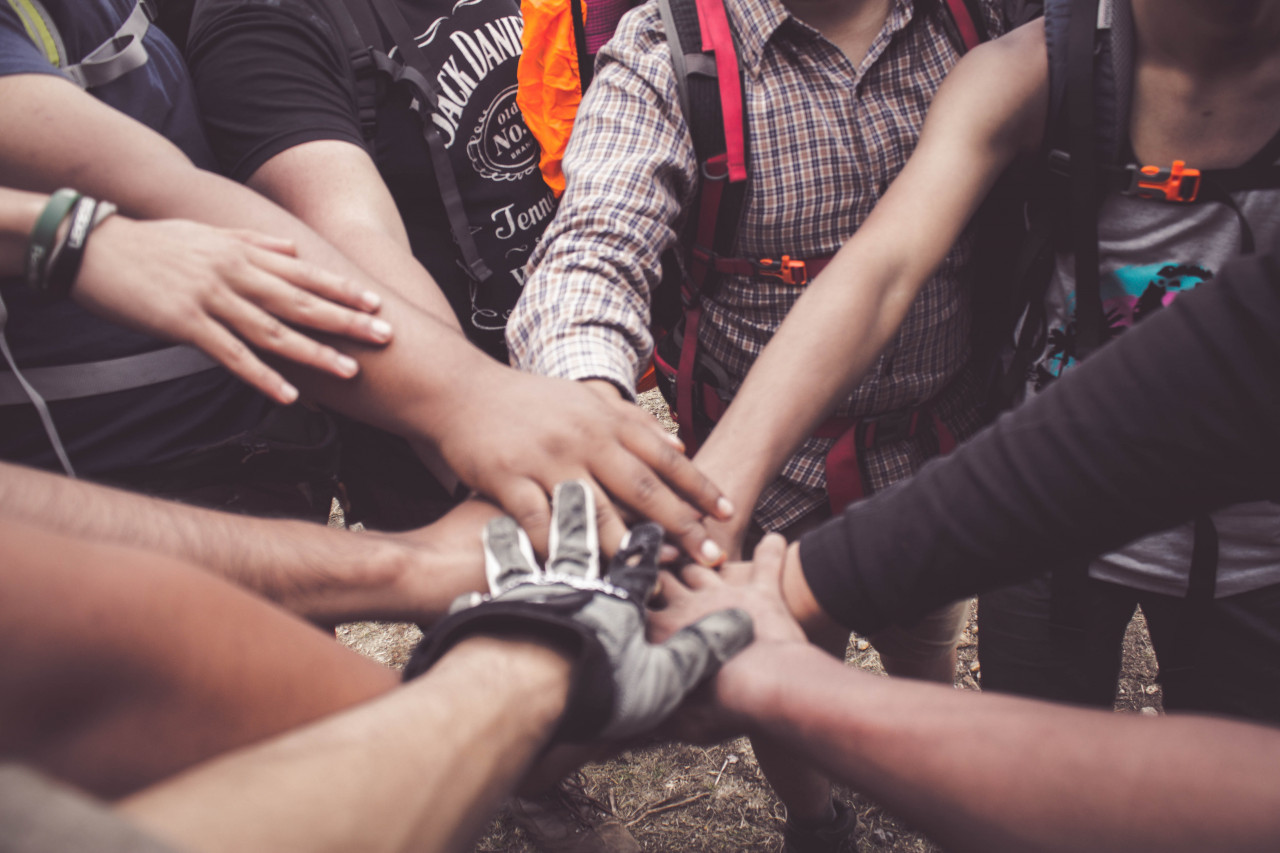 Multiple people placing arms together.