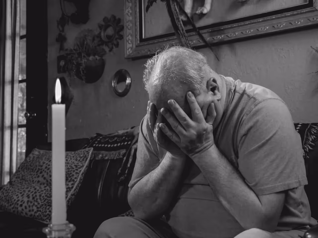 An old man bowing his head in grief.