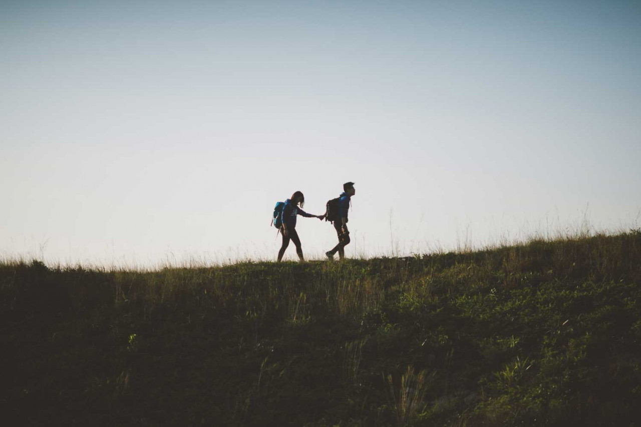two people hiking on a hill