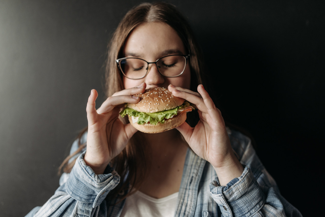 A lady stress-eating a burger.