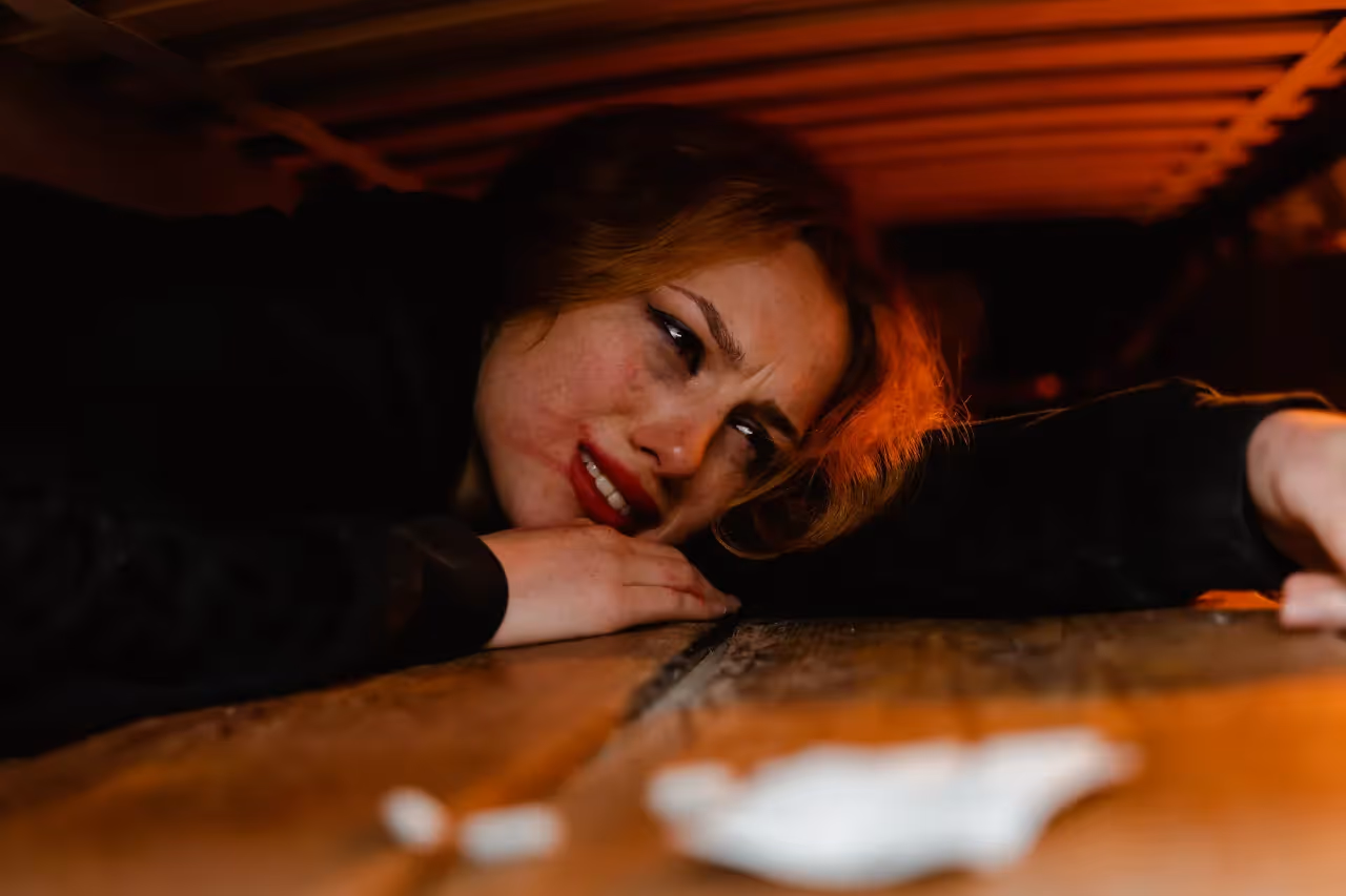 A lady crying under her bed.