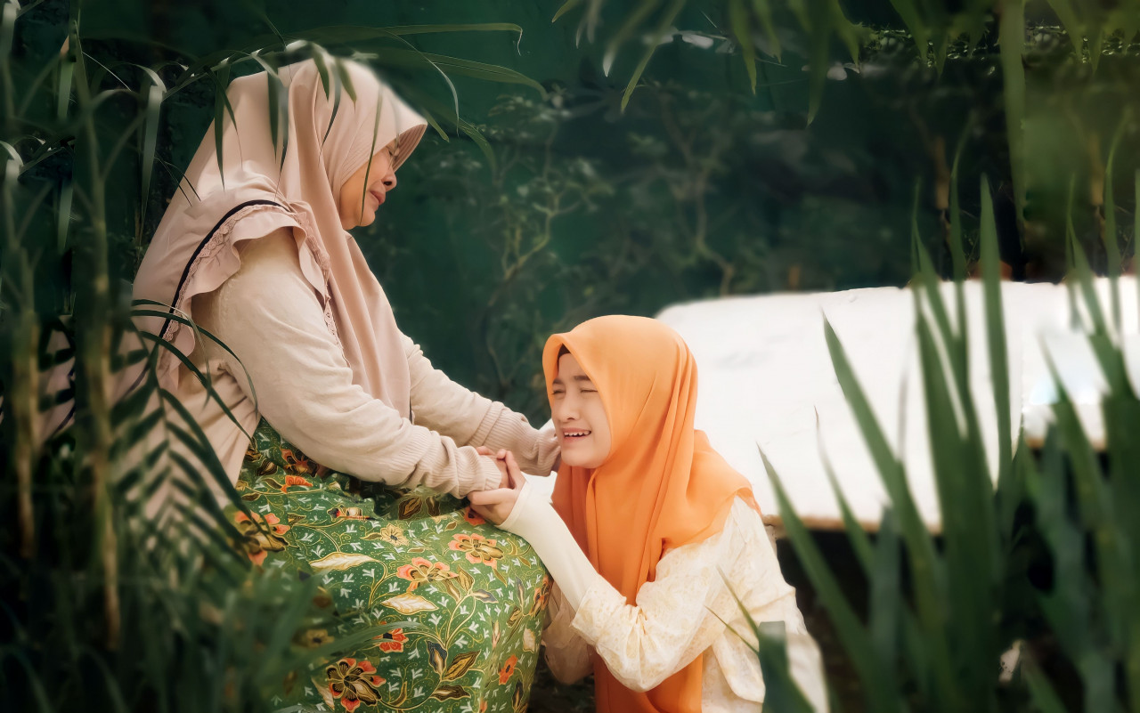 An adult female consoling a young girl.
