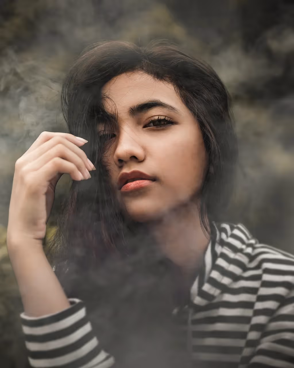 A young girl wearing a striped shirt surrounded by smoke