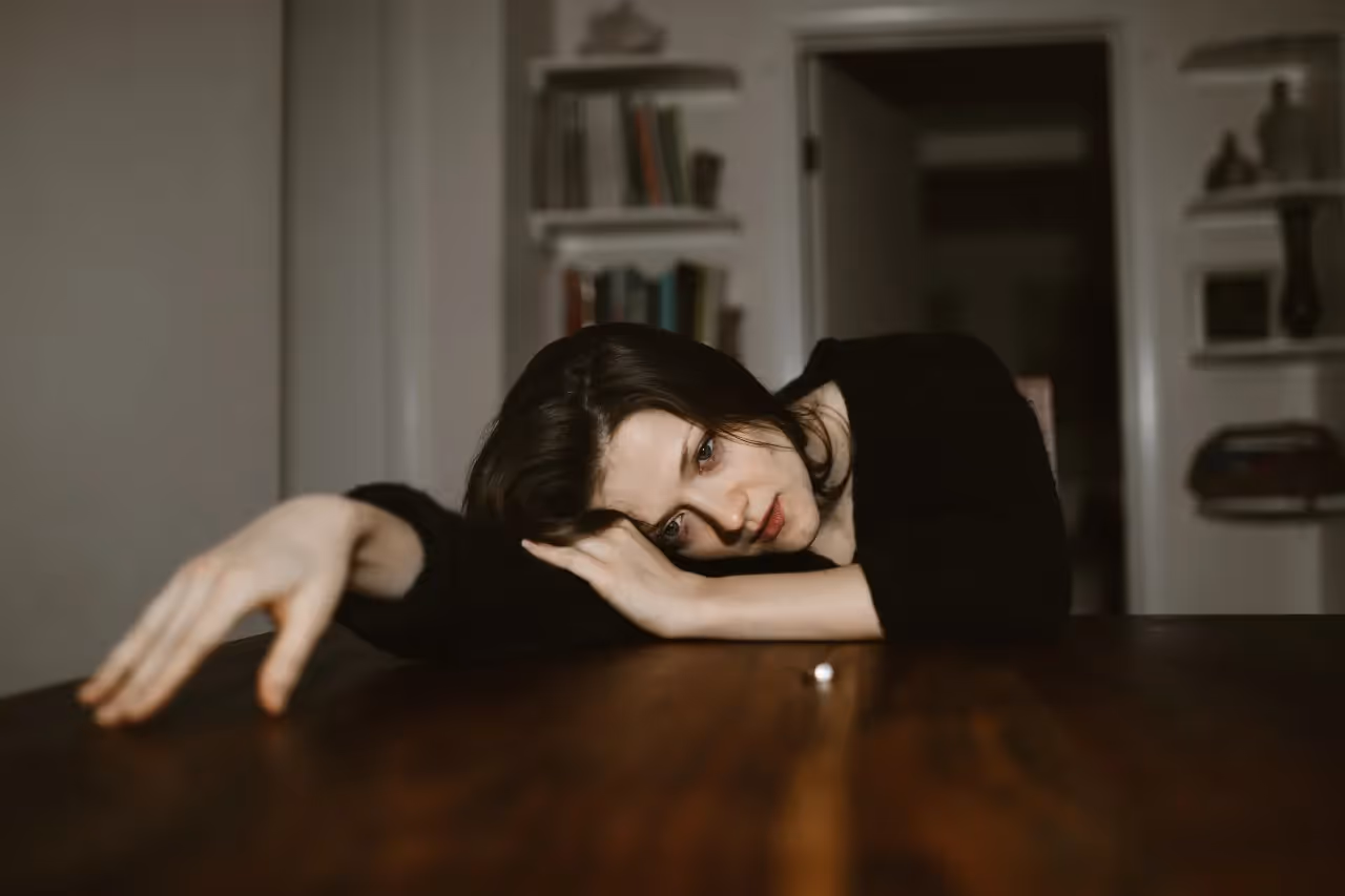 A sad woman resting on a table.