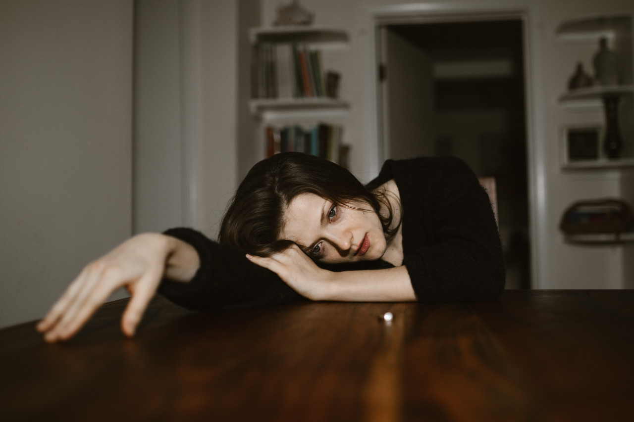 A sad woman resting on a table.