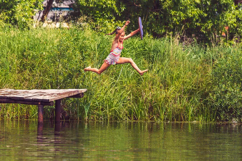 a young person jumping into a lake