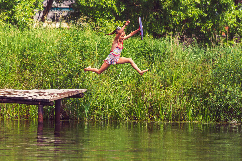 a young person jumping into a lake