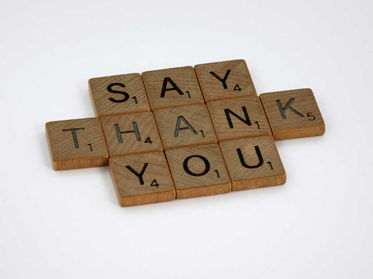 scrabble tiles that spell out say thank you