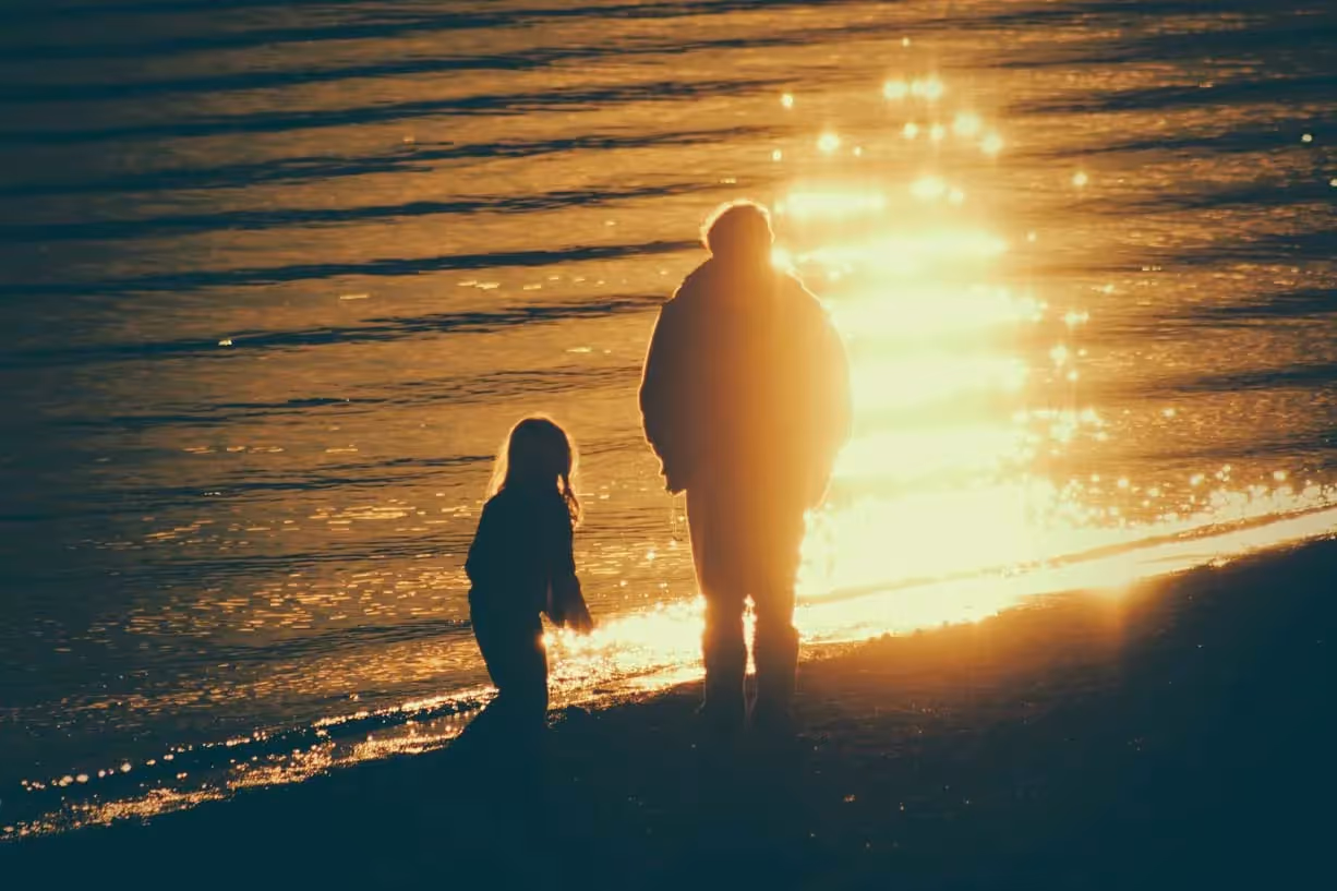 a parent and child standing by a lake