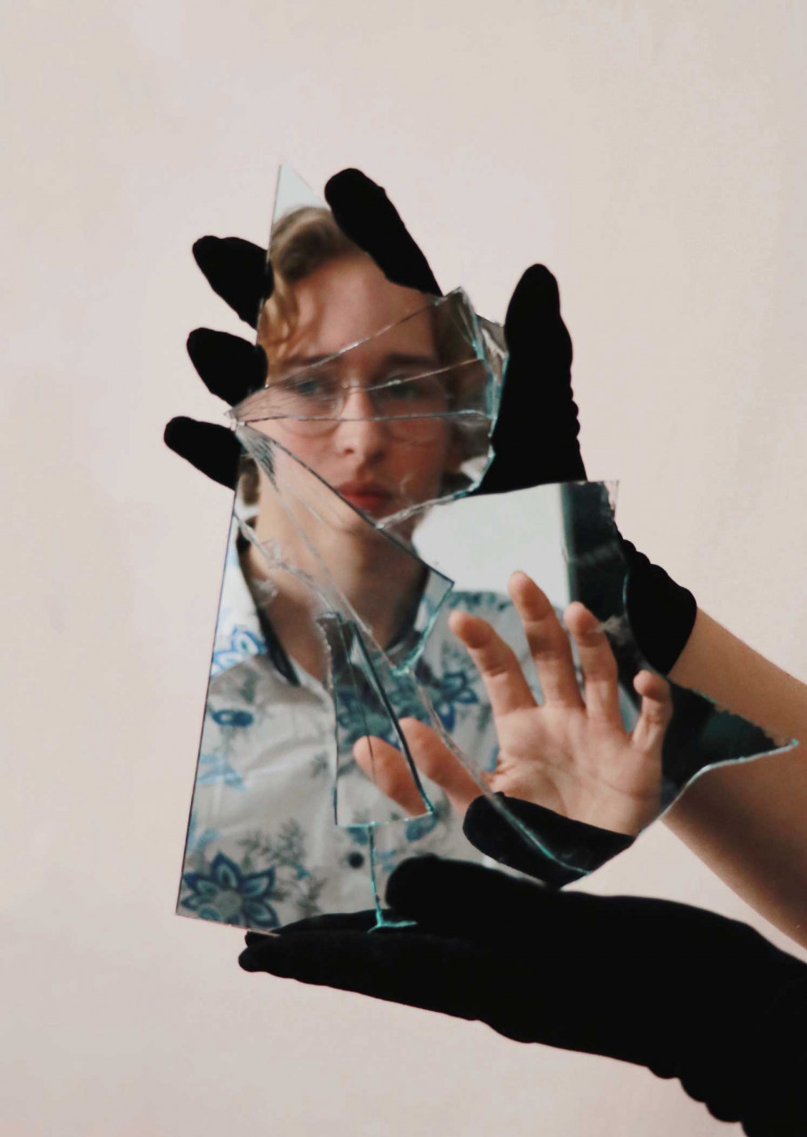 a young person looking at a broken mirror