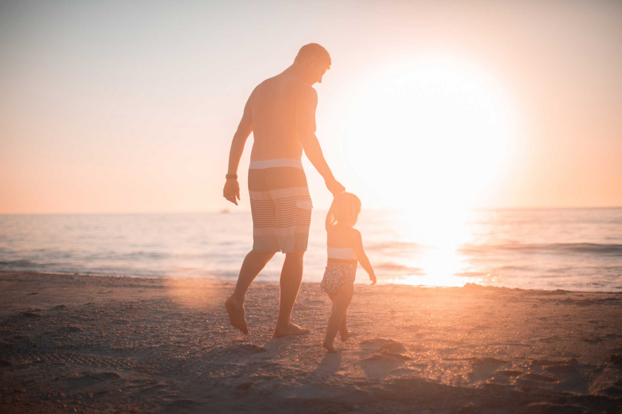 a father and his child walking on the beach