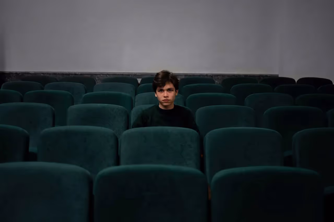 a young teenager sitting in a cinema