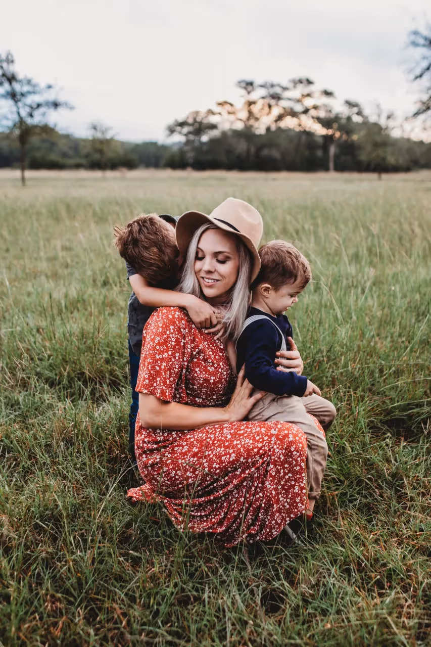 a mom and her two young kids in a grass field