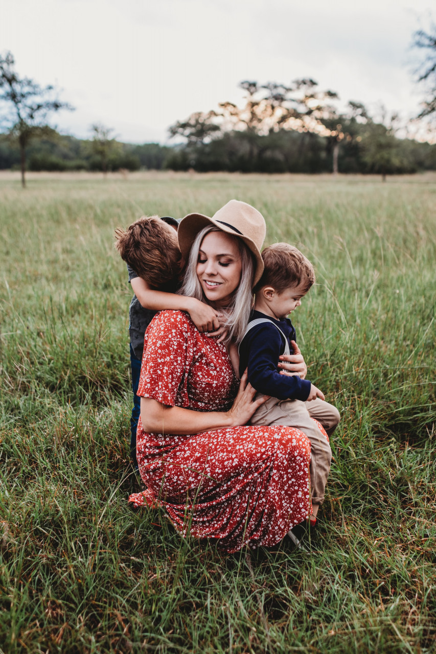 a mom and her two young kids in a grass field