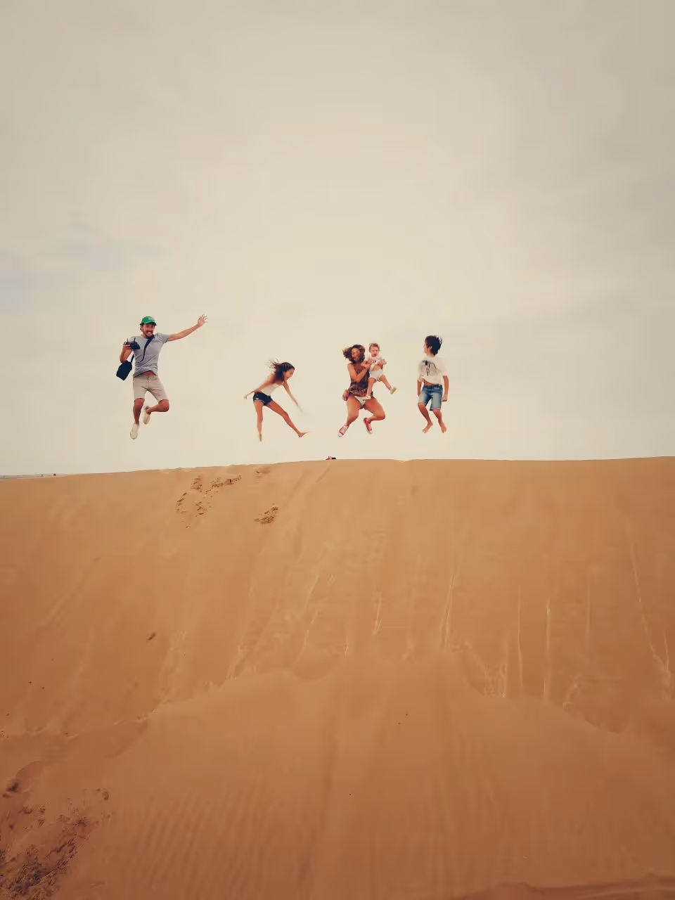 A family jumping in the air on sand dunes
