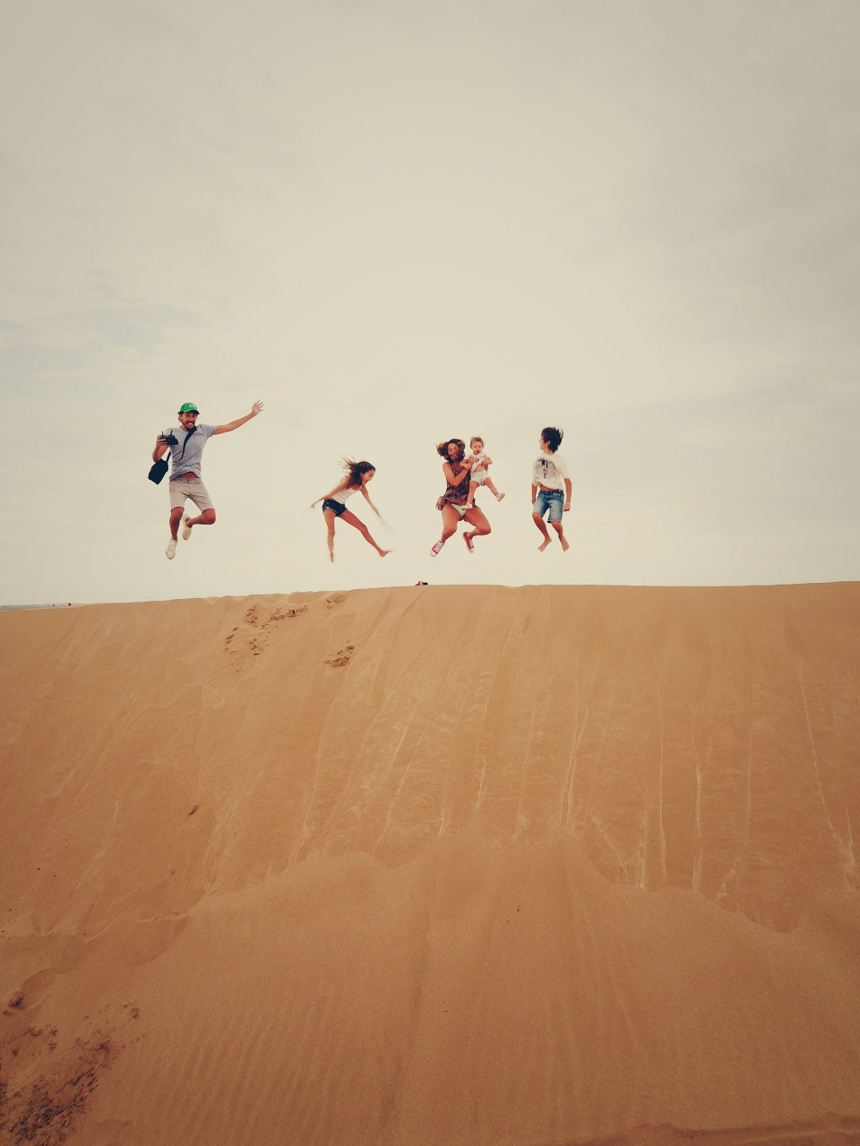 A family jumping in the air on sand dunes
