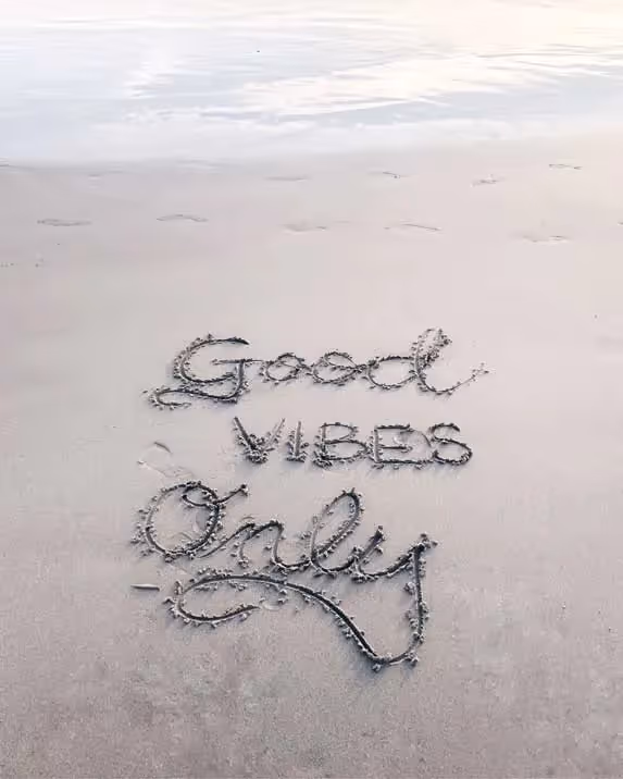 a message written in sand on a beach that says good vibes only