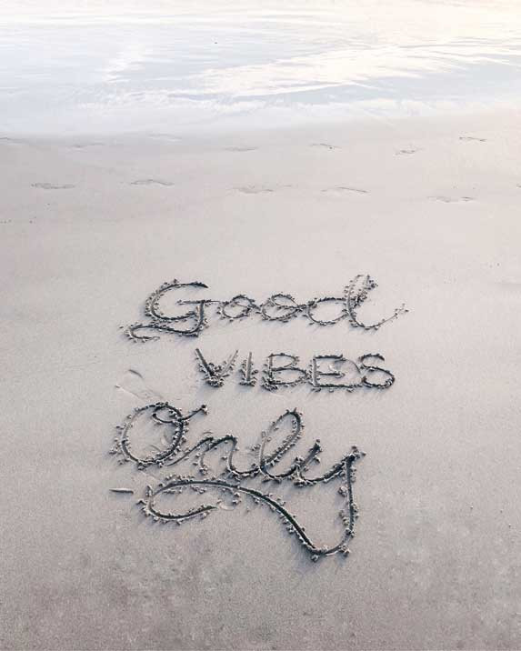 a message written in sand on a beach that says good vibes only