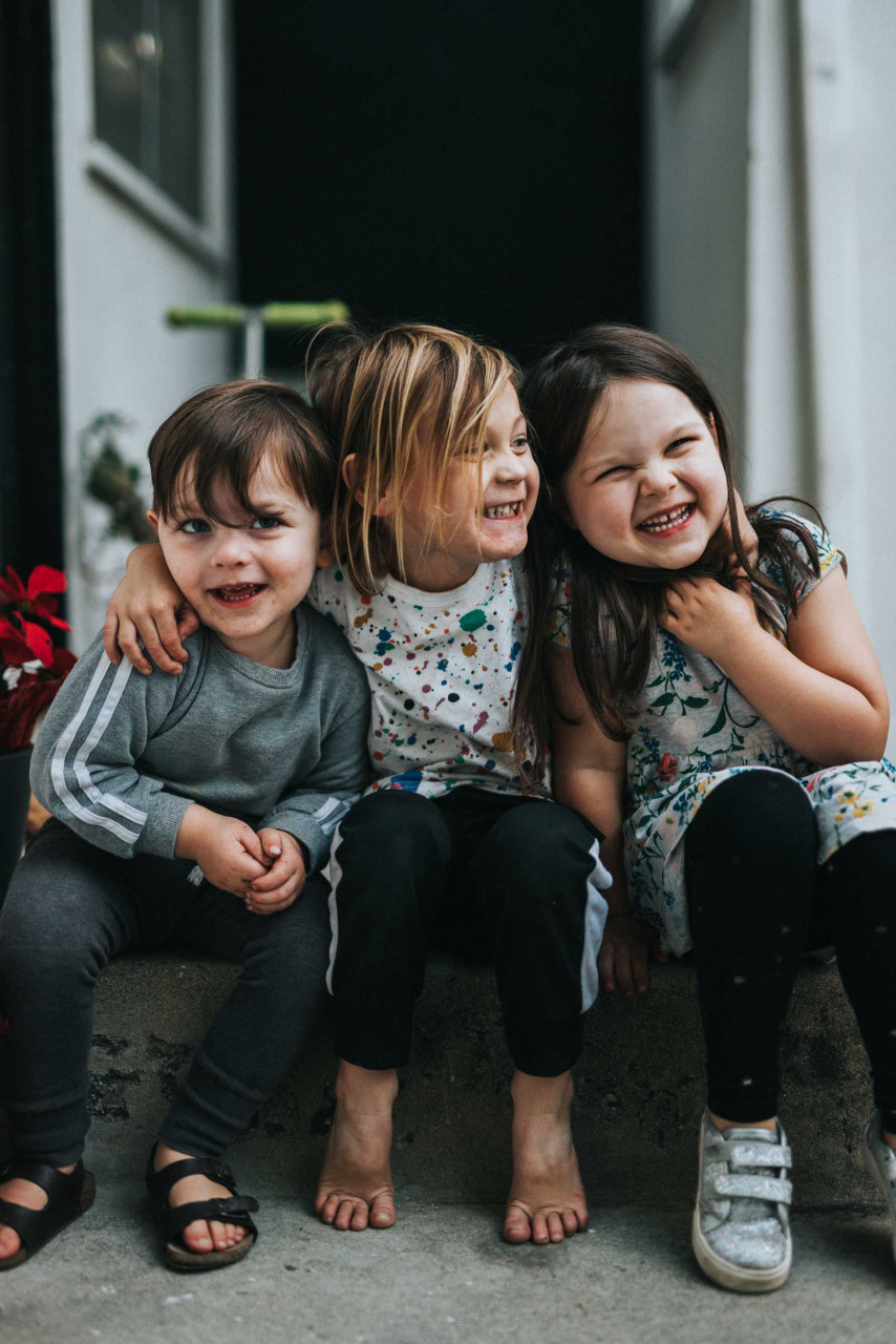 three kids sitting together and hugging